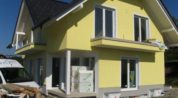 Rumena fasada hiše z balkonom in belimi obrobami